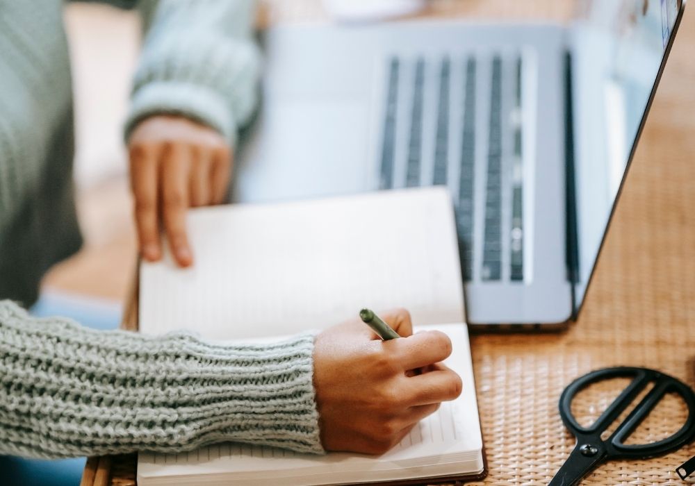 Woman journaling on a notebook on her desk.