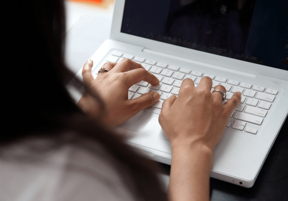 Woman with dark hair, typing on her laptop.